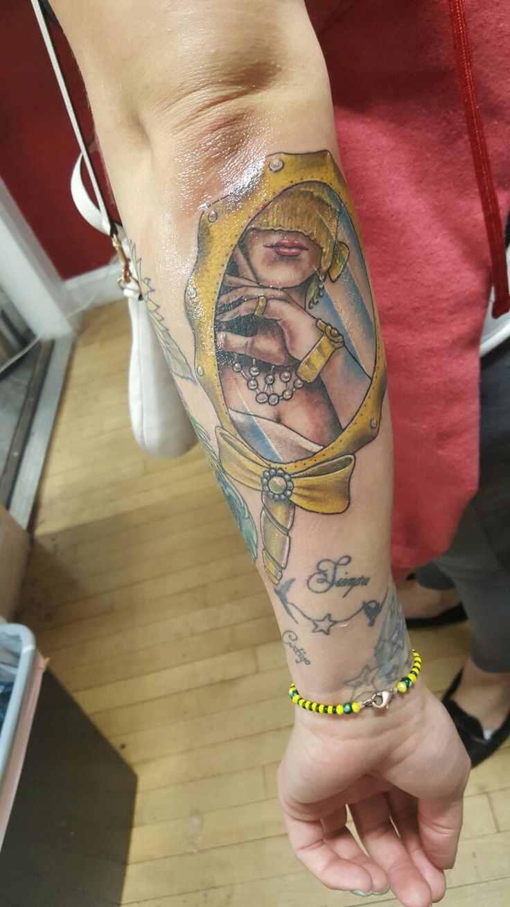 a woman's arm with tattoos on it and an image of a woman in a mirror