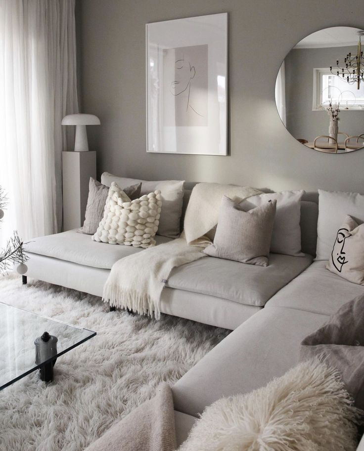 a living room filled with lots of white furniture and pillows on top of a rug