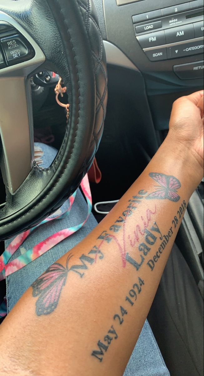 a person with a tattoo on their arm in a car, holding the steering wheel