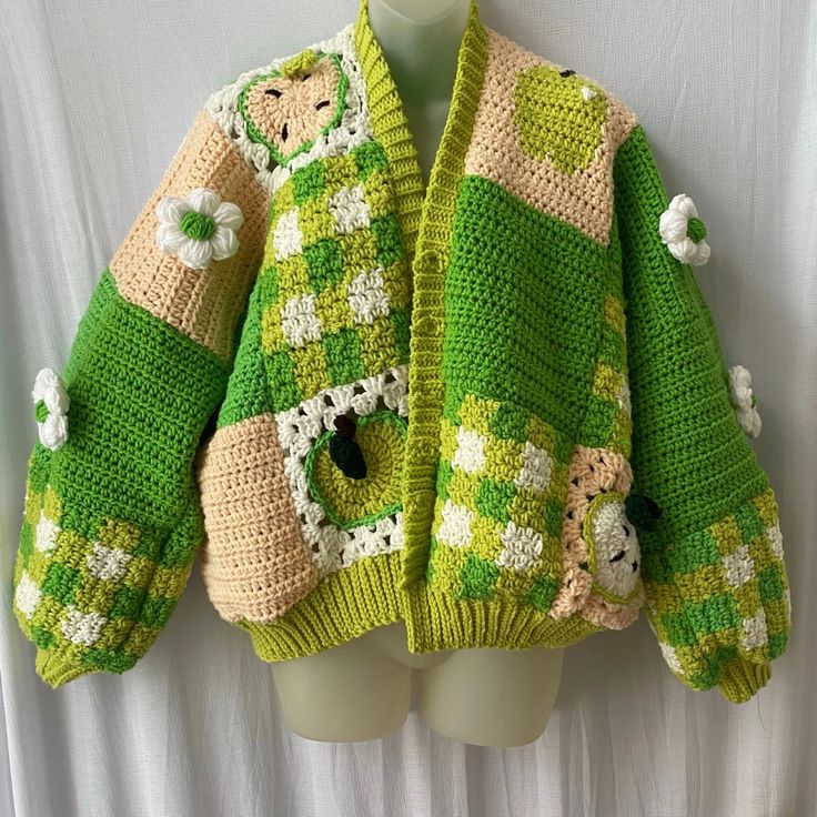 a crocheted green and white jacket on a mannequin's head