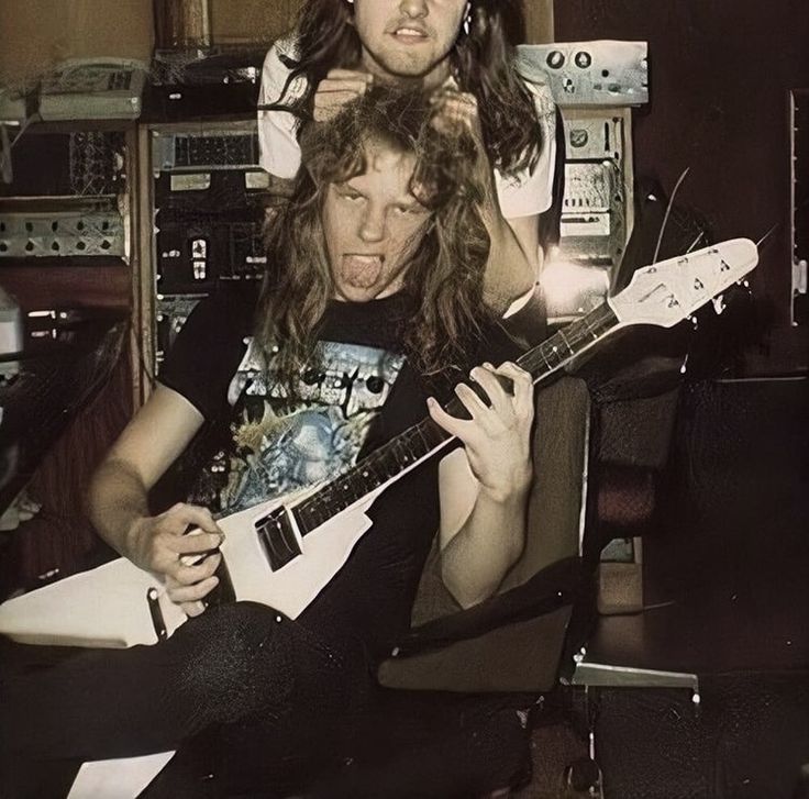 a man sitting in a chair holding a guitar and looking at the camera with his mouth open