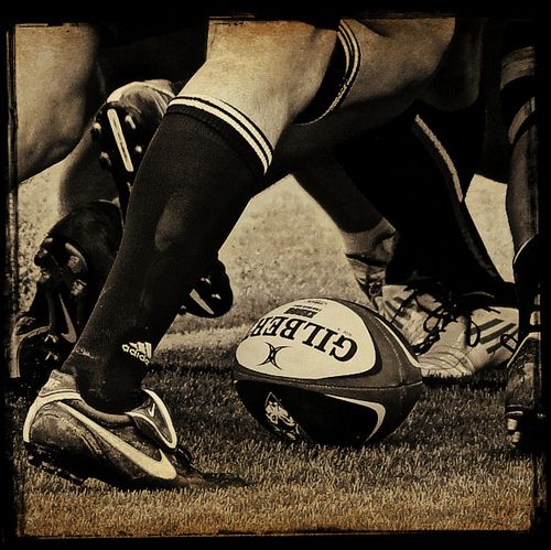 a rugby ball is sitting on the ground next to two players'legs and feet