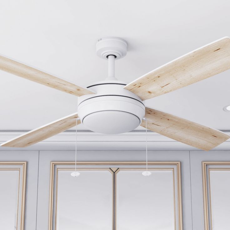 a white ceiling fan with wooden blades in a room