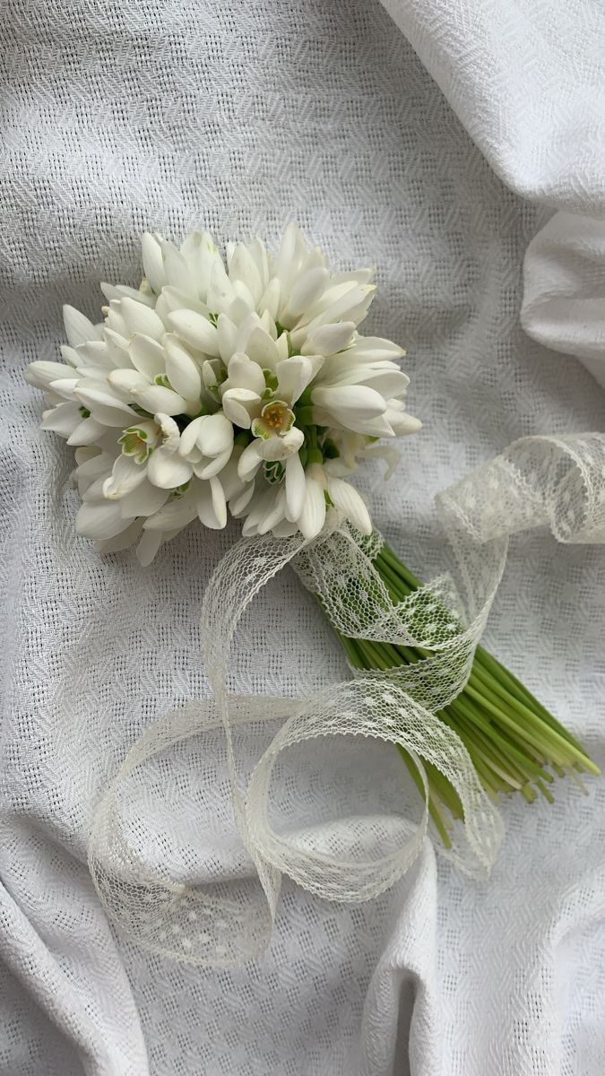 a bouquet of white flowers sitting on top of a white cloth covered tablecloth,