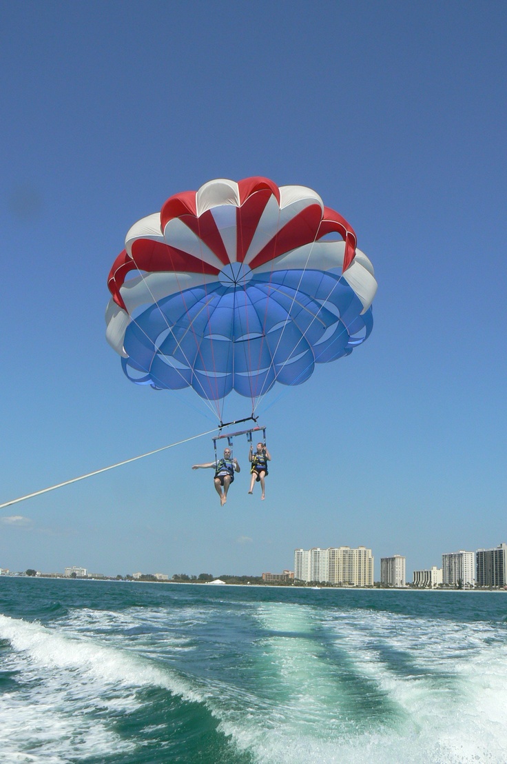 two people parasailing in the ocean on a sunny day