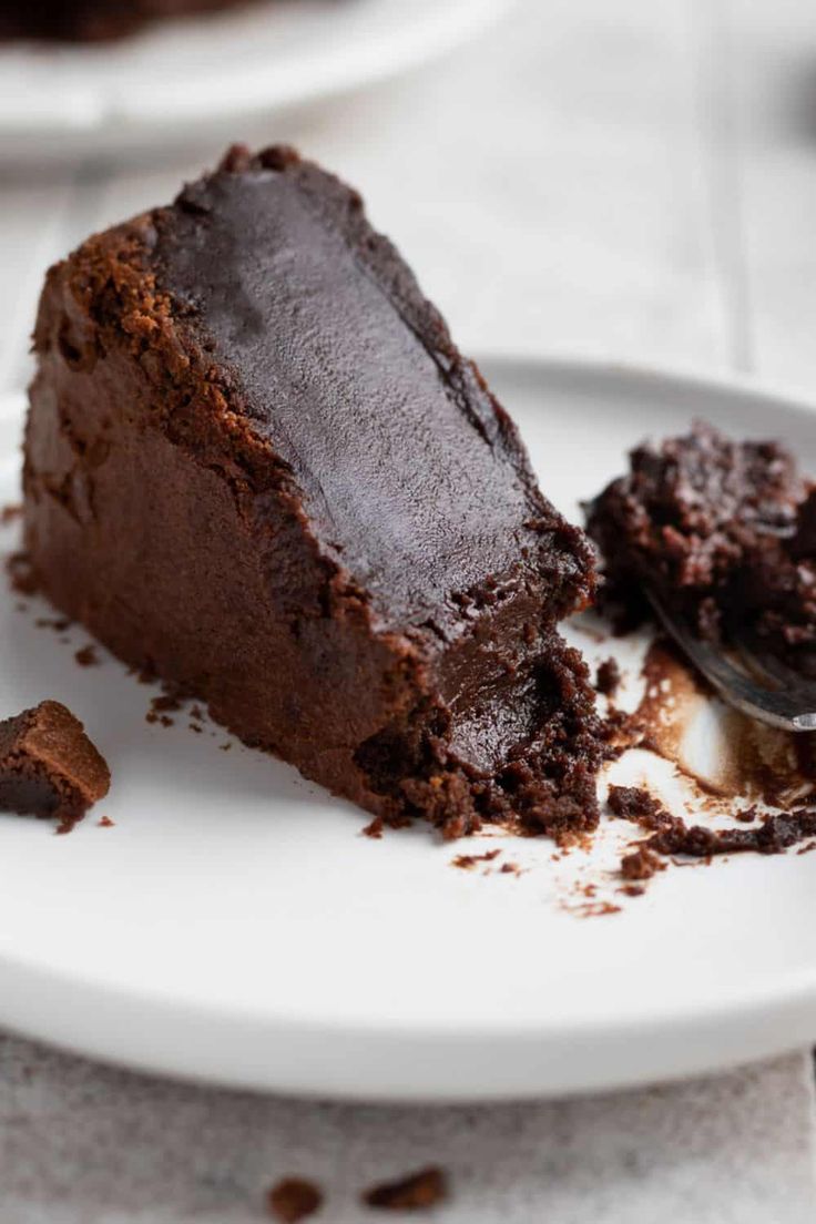 a piece of chocolate cake on a white plate with a bite taken out of it