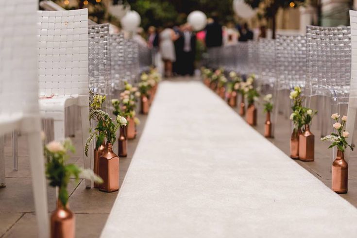 an aisle lined with chairs and vases filled with flowers