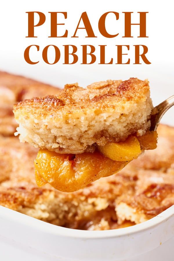 a piece of peach cobbler being lifted from a casserole dish with a fork