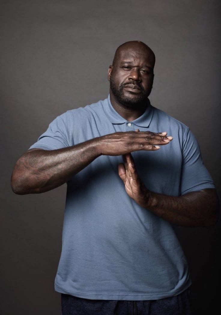 a man in blue shirt holding his hands out to the side with both hands together