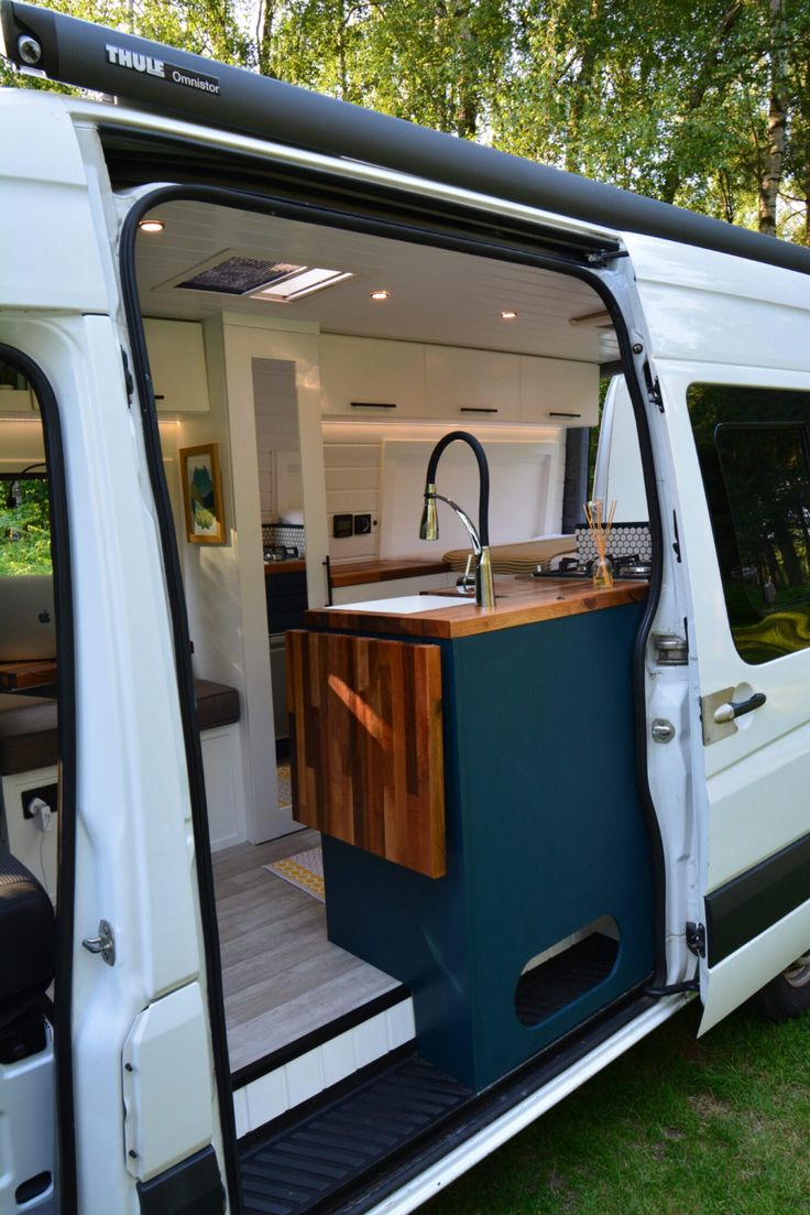 an open van door showing the kitchen and living area inside it, with wood counter tops on both sides