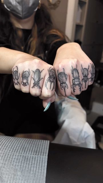 a woman with tattoos on her fingers and hands is sitting at a table while wearing a surgical mask