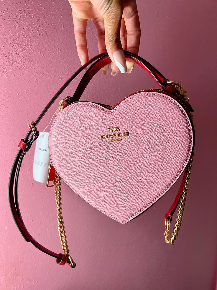 The Coach Heart Bag is the new it bag that recently dropped at the Coach Outlets. It's hard to find, but check out my blog to see how I was able to get one! Heart Coach Purse, Coach Bags Heart, Pink Coach Bag Aesthetic, Coach Valentine Bag, Coach Heart Bag Outfit, Heart Coach Bag, Coach Heart Purse, Coach Bag Pink, Pink Luxury Bag