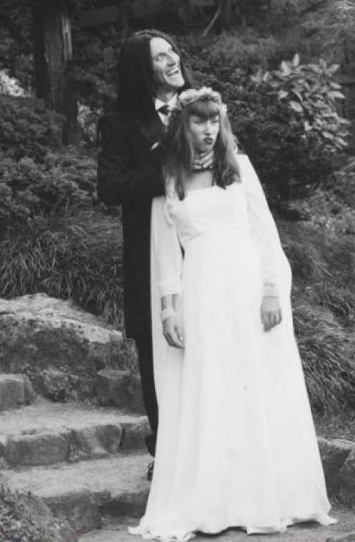 an old black and white photo of two people dressed in wedding attire standing on steps