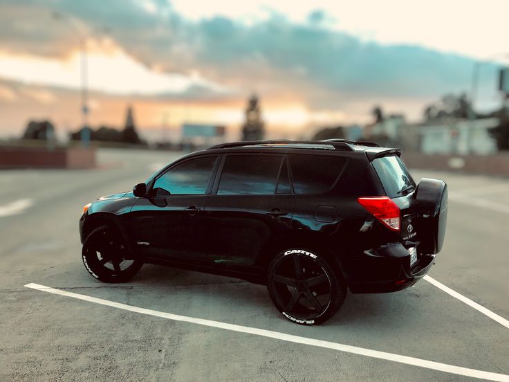 a black suv parked in a parking lot with the sun shining down on it's horizon