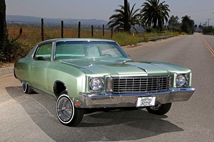 an old green car is parked on the side of the road