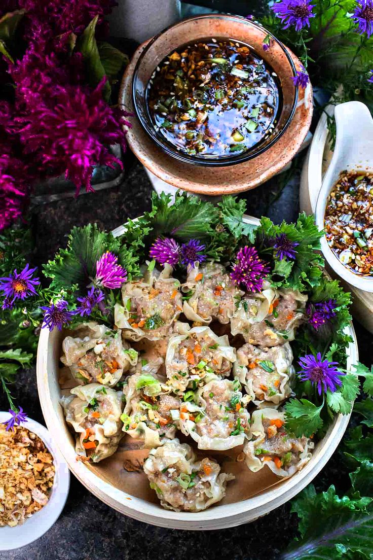 several bowls filled with food next to purple flowers