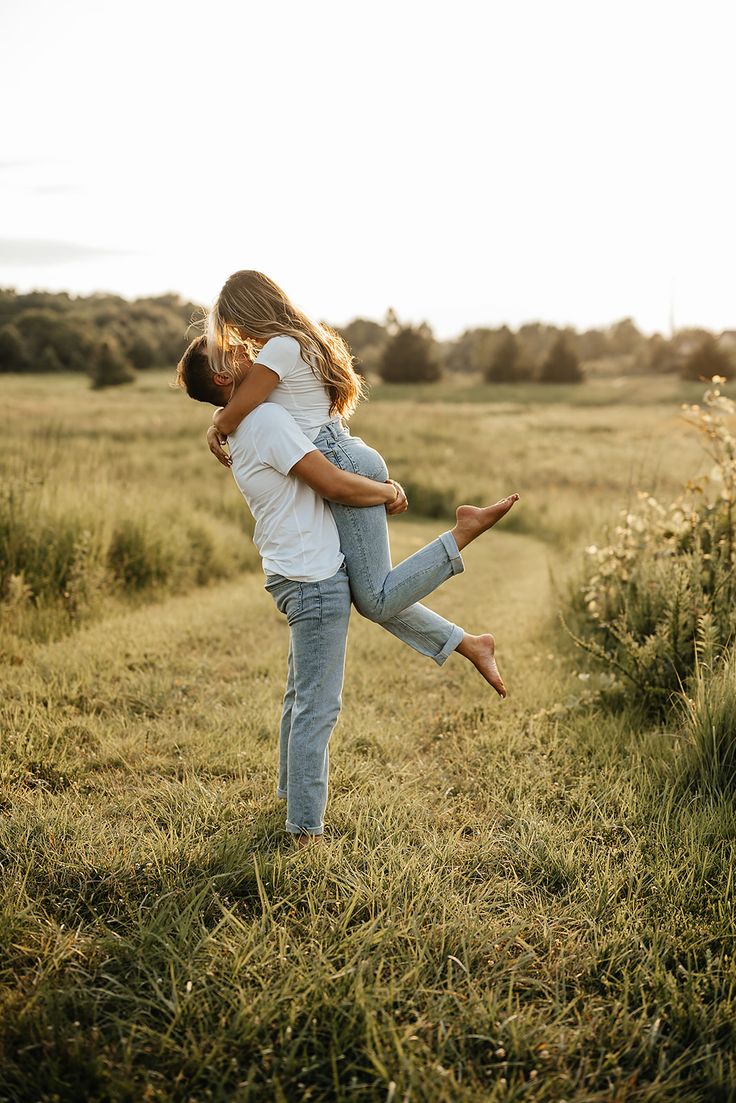 a man and woman hug in the middle of a field