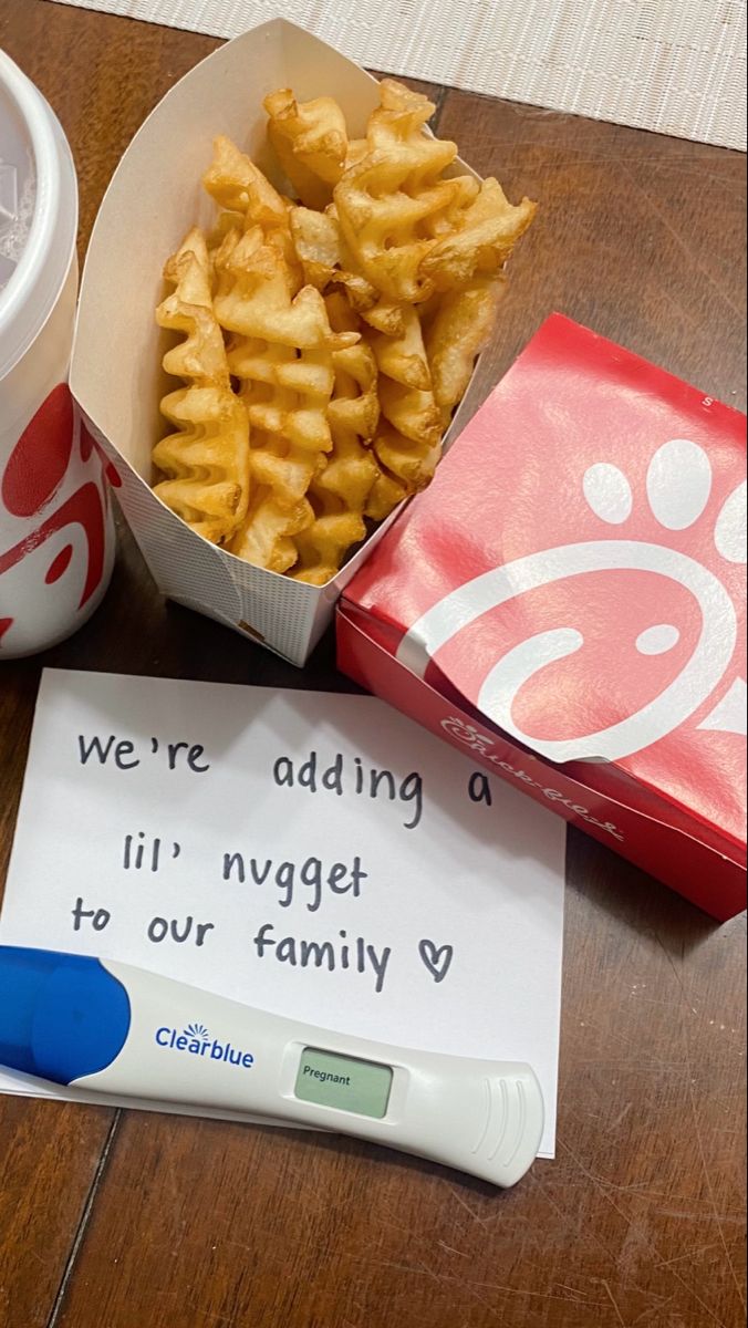 there is a box of fries next to a cup of soda and a sign that says we're adding a lil nugget to our family