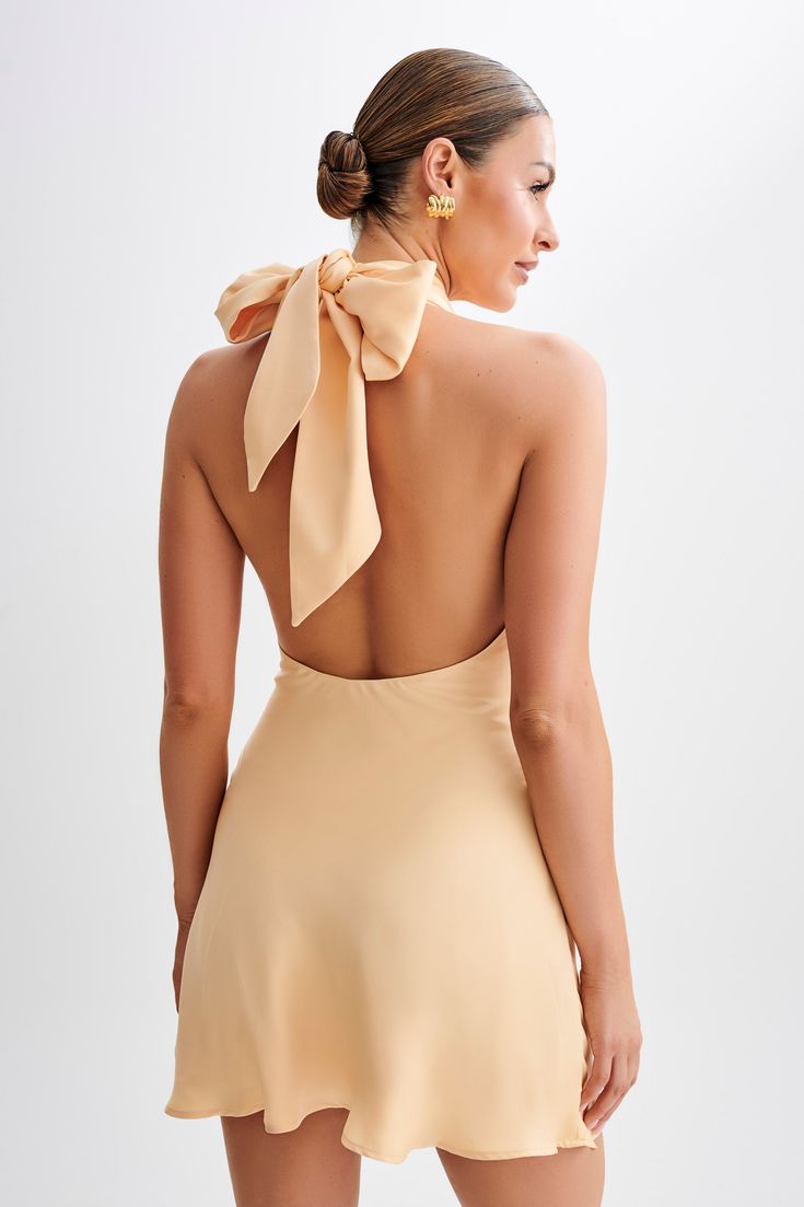 For the perfect day.Presenting the FRANCINE Satin Halter Mini Dress, a stunning piece that effortlessly combines elegance and allure. Featuring a gathered bust and halter neckline, this dress exudes feminine charm with every detail. The tie back neck adds a touch of sophistication, while the crossover neckline detail enhances its visual appeal. With its mini length and low back, it offers a flattering silhouette that's perfect for any occasion. Lined for comfort and coverage, and with a side zip Feminine Bow Tie Backless Mini Dress, Chic Mini Dress With Gathered Neckline And Fitted Bodice, Elegant Tie-back Midi Dress For Garden Party, Flirty Bridesmaid Dress With Tie Back, Feminine Tie Back Mini Dress For Bridesmaid, Feminine Mini Dress With Bow Tie Back For Wedding, Flirty Backless Dress With Bow Tie Back, Summer Bridesmaid Mini Dress With Ruched Bodice, Feminine Bow Tie Back Mini Dress For Wedding