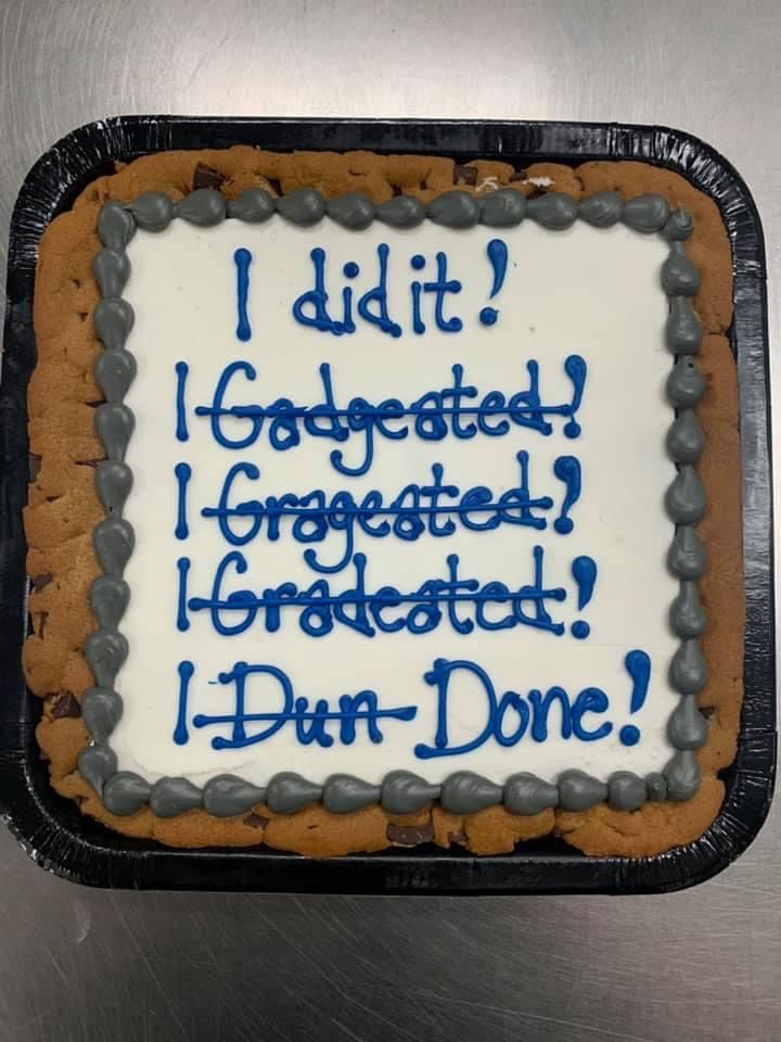 a cake that is sitting on top of a metal surface with words written in blue and white