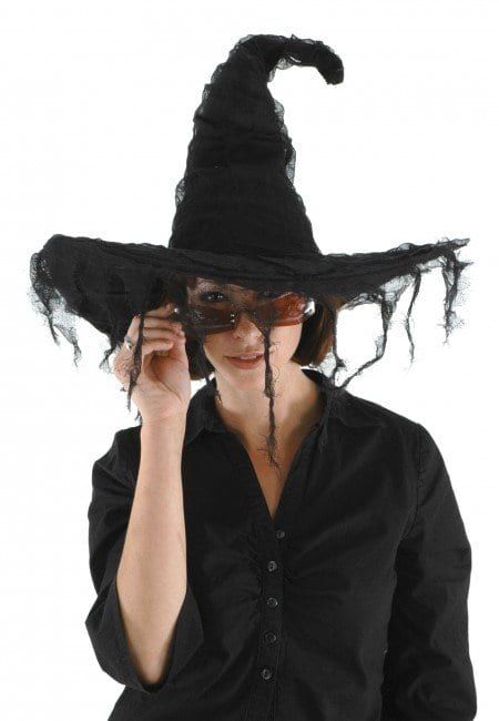 a woman wearing a black witches hat and holding her hands up to her face with one hand