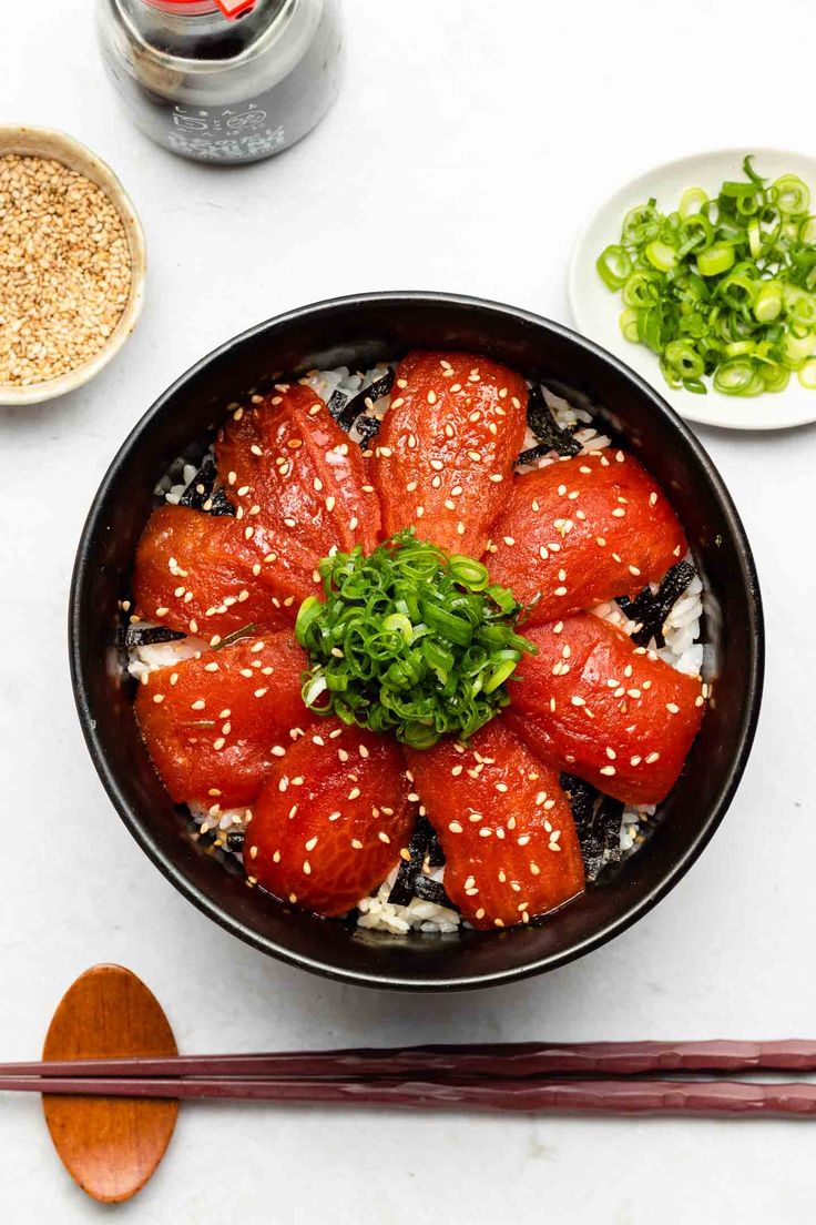 sushi in a bowl with chopsticks next to it on a white table