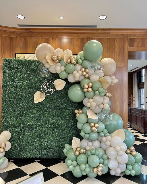 balloons and greenery are arranged in the shape of a tree on a black and white checkered floor