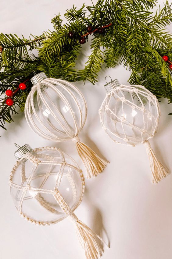 two glass ornaments on a white surface surrounded by greenery