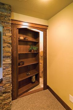 an open bookcase in the corner of a room next to a brick wall and door