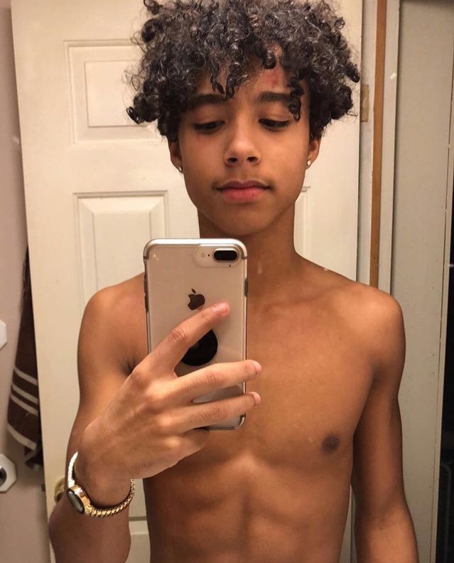 a shirtless young man taking a selfie with his cell phone