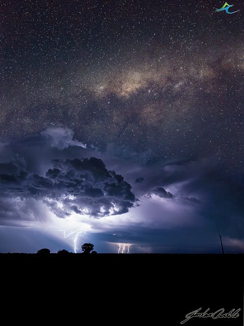 the night sky is filled with stars and clouds, while lightning strikes in the distance