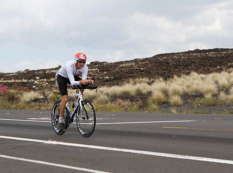 a man riding a bike down the middle of a road in front of a hill