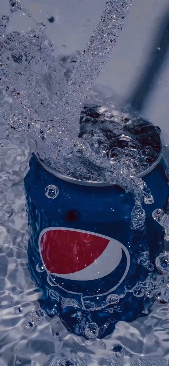 a can of pepsi is splashing into the water