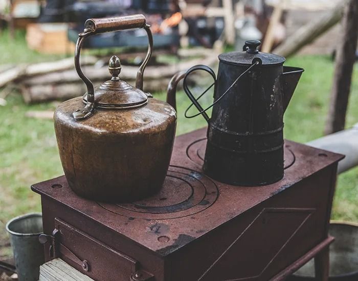 an old fashioned tea kettle sitting on top of a wooden box next to a coffee pot