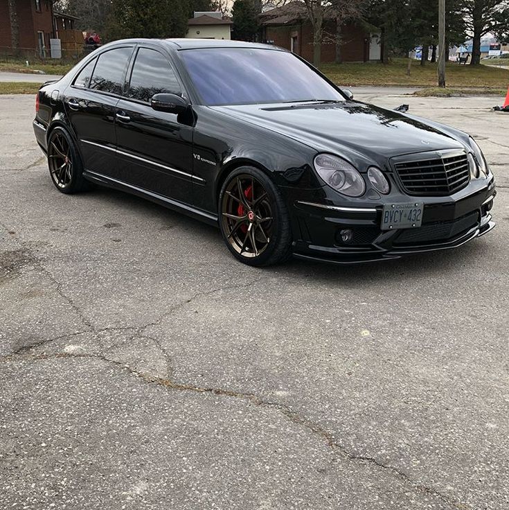 a black car parked in a parking lot next to another car with red rims