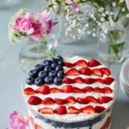 an american flag cake with strawberries and blueberries on the top is sitting on a table