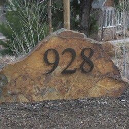 a large rock with the number twenty nine on it in front of a house and trees