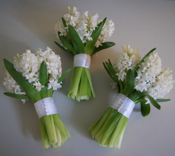 three bouquets of white flowers sitting on top of a table next to each other