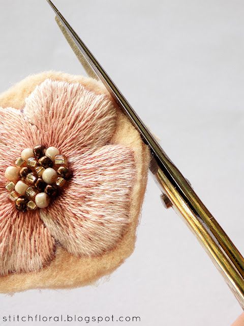 the needle is being used to make a flower brooch