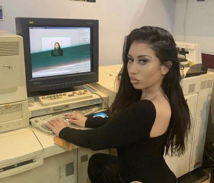 a woman sitting in front of a computer with a keyboard and monitor on it's desk