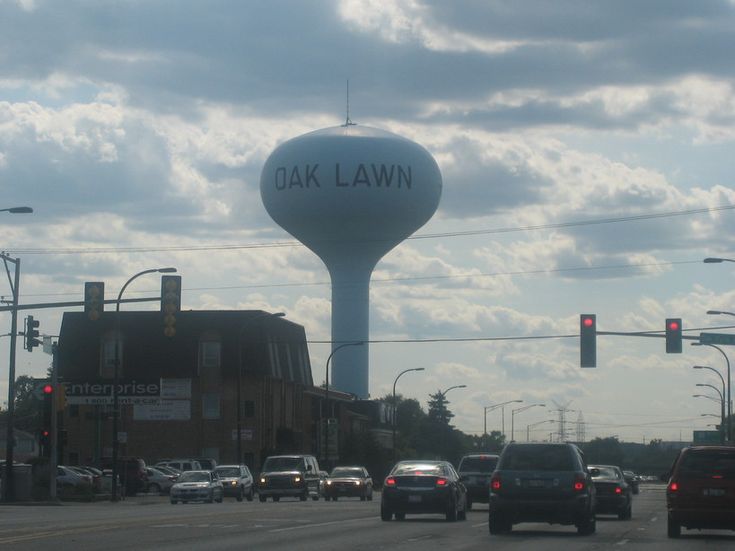 cars driving down the road in front of a water tower