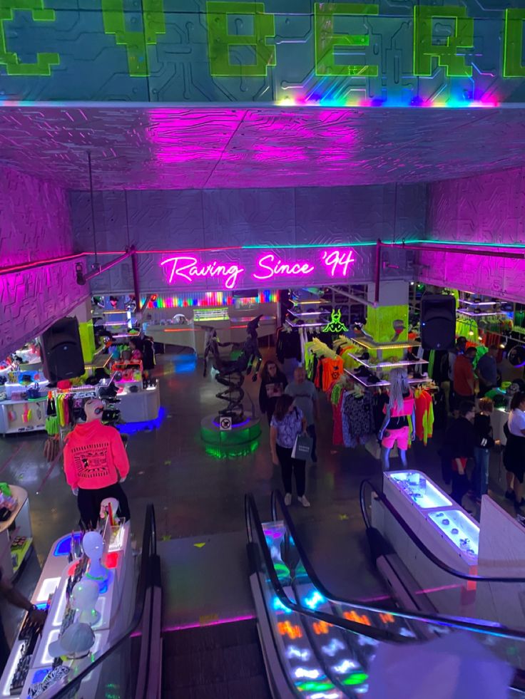 an indoor mall with neon lights and people shopping