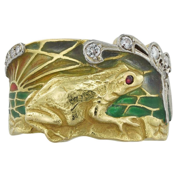 An Art Nouveau enamel ring by Marsiera, depicting a finely engraved gold frog in front of a multi-colour plique-à-jour enamel sunset, flanked by old brilliant-cut diamonds, circa 1910, signed Masriera, bearing later French import marks for 18ct gold and platinum, the head measuring 2.2 x 1.5cm, finger size L, gross weight 12.6 grams. This art noveau ring depicts a romantic landscape in which a frog sits beneath stars. Masriera, the Spanish jeweller, often drew inspiration from nature and his wor Mens Bands, 1920s Ring, Romantic Landscape, Plique A Jour, Frog Ring, Frog Jewelry, Vintage Diamond Ring, Inspiration From Nature, 1920s Vintage