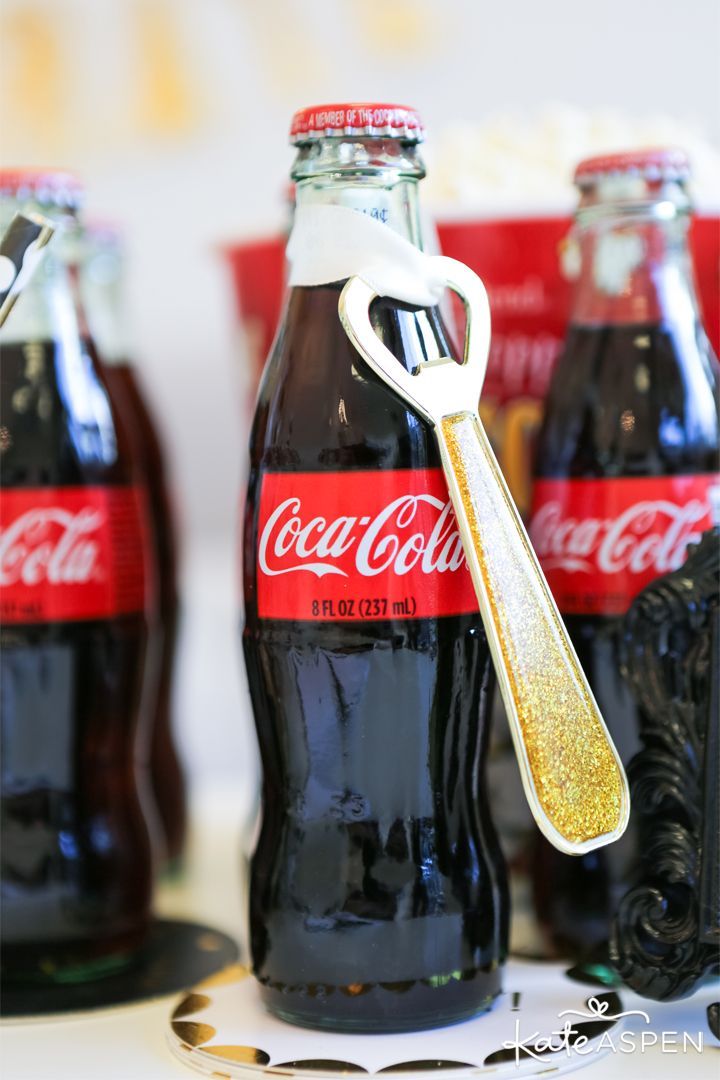 coca - cola bottles are lined up on a table with a gold spoon in the bottle