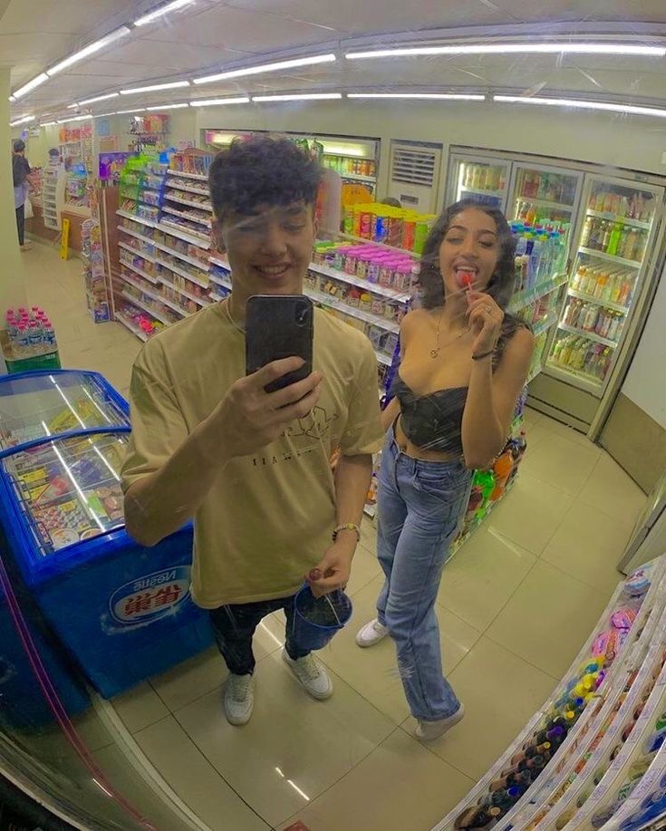 a man and woman are looking at their cell phones in the store's selfie mirror