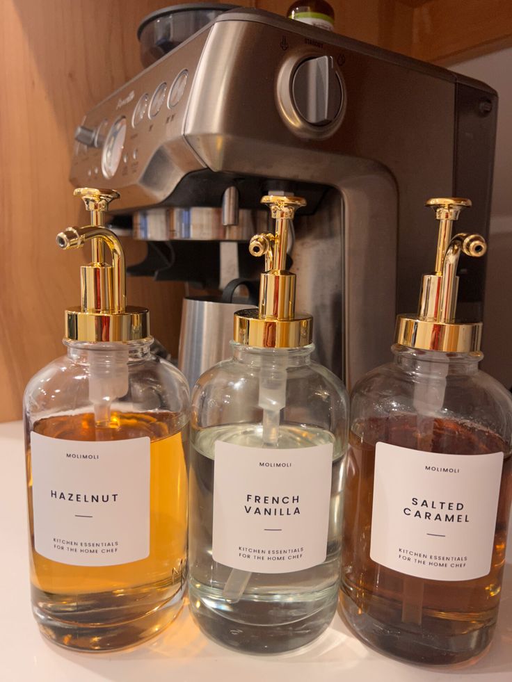 three different types of hand soaps sitting on a counter next to an espresso machine