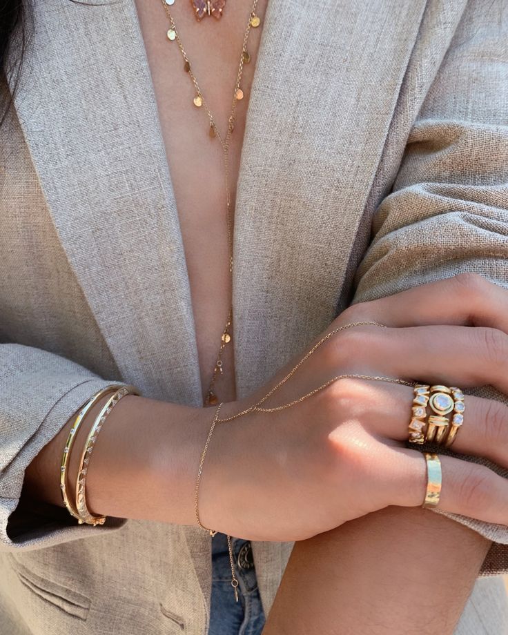 a woman wearing gold rings and bracelets holding onto her arm with both hands on the other hand