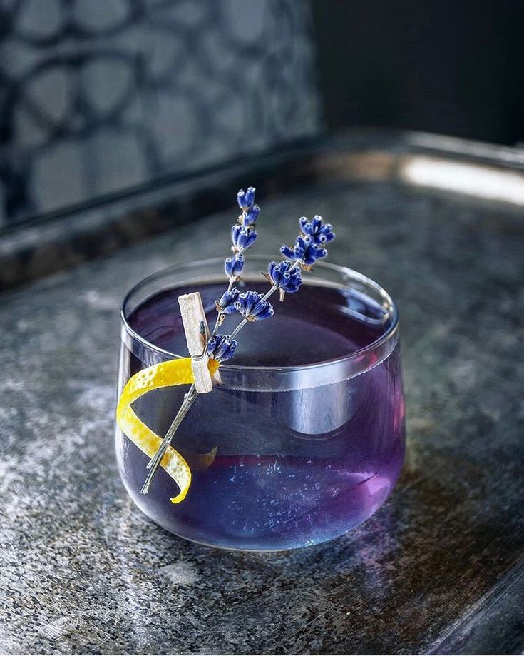 a glass filled with purple liquid sitting on top of a counter next to a yellow ribbon