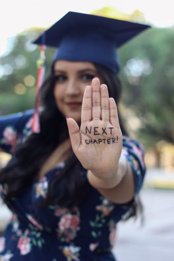 a woman wearing a graduation cap and gown holds her hand up with the word next i charter written on it