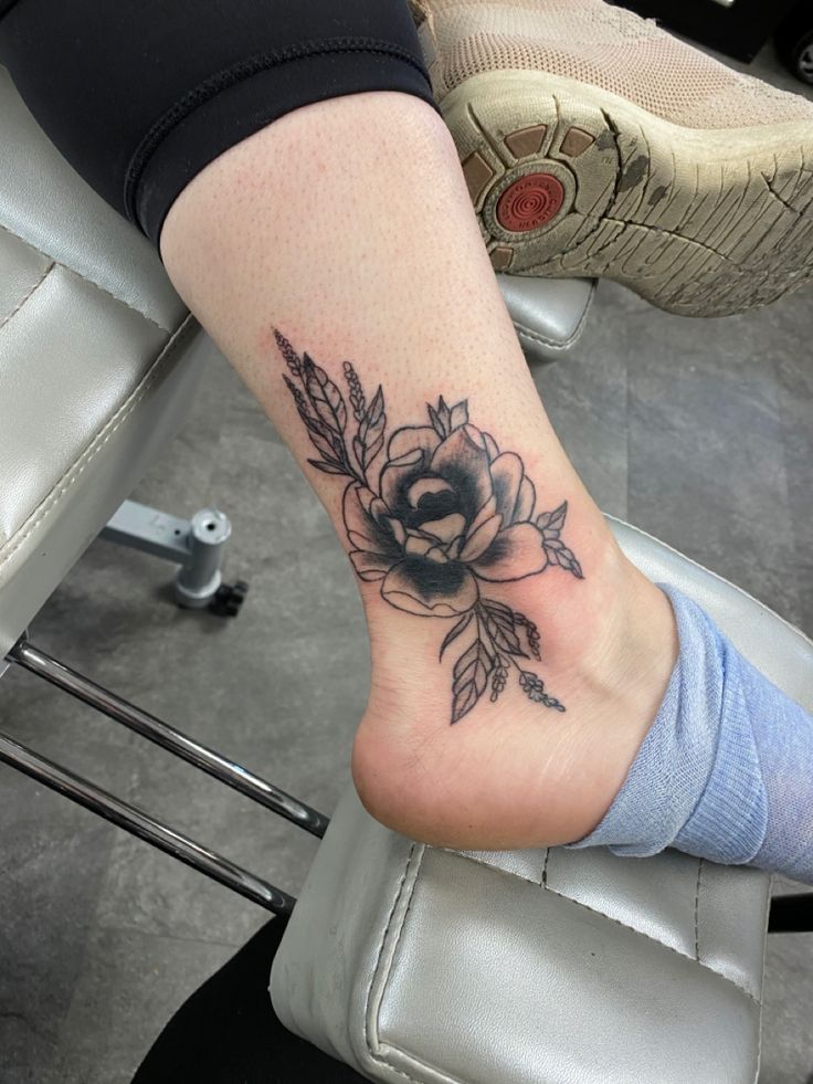 a woman's foot with a rose tattoo on the top of her left leg